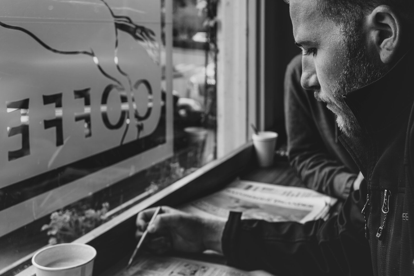 a man sitting at a window reading a newspaper